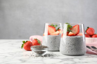 Çilekli lezzetli chia pudingi ve beyaz mermer masada nane şekeri.