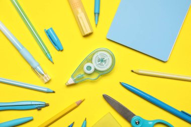 Sarı zemin üzerinde farklı kırtasiye malzemesi, düz yatış