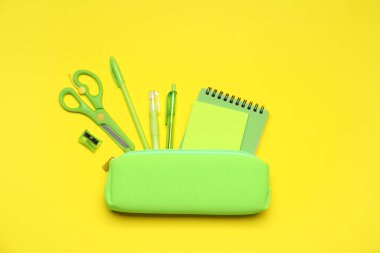 Kalem kutusu ve sarı zemin üzerinde farklı kırtasiye malzemesi, düz yatıyordu