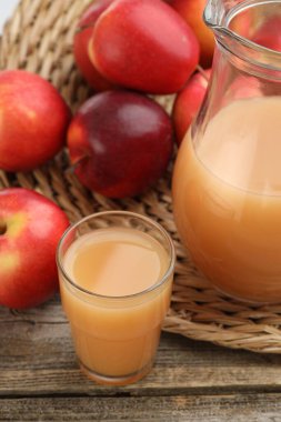 Lezzetli elma suyu ve taze meyveler ahşap masada, yakın plan.