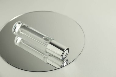 Işık arkaplanında bir şişe serum ve ayna, metin için boşluk