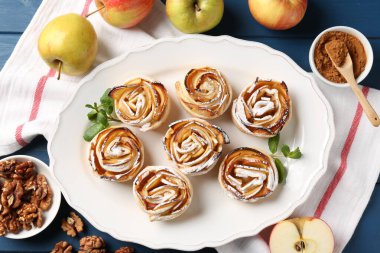 Mavi ahşap masada servis edilen pudra şekerli elma gülleri.