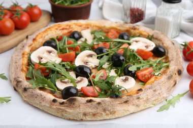 Kiraz domatesli lezzetli pizza, siyah zeytin, mantar ve roka beyaz masada, yakın plan.