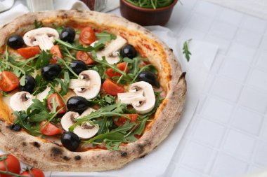 Kiraz domatesli lezzetli pizza, siyah zeytin, mantar ve roka, beyaz fayanslı masa, yakın çekim. Metin için boşluk