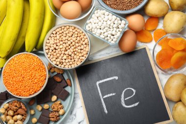 Demir ve beyaz mermer masa üzerinde Ferrum sembolü olan küçük karatahta bakımından zengin farklı ürünler. Anemi için diyet planı