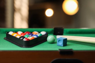 Birçok renkli bilardo topu üçgen rafında, işaretler ve tebeşirler yeşil masada kapalı, yakın plan