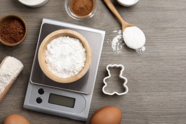 Mutfak terazisinde bir kase kabartma tozu ve ahşap masa üzerindeki diğer ürünler var. Metin için boşluk