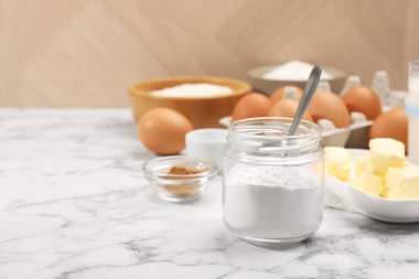 Kavanozdaki kabartma tozu ve beyaz mermer masadaki diğer ürünler, yakın plan. Metin için boşluk