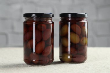 Kavanozlarda turşulu yeşil zeytin beyaz desenli masa, yakın çekim.