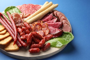 Mavi arka planda farklı tütsülenmiş sosisler ve diğer atıştırmalıklar, yakın plan