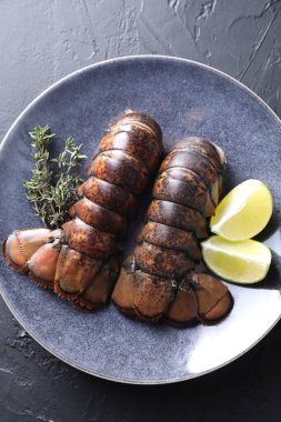 Çiğ ıstakoz kuyruğu, kireç ve kekik siyah masada, üst manzara