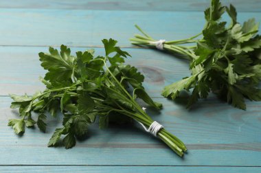 Mavi ahşap masada taze maydanoz, yakın plan.