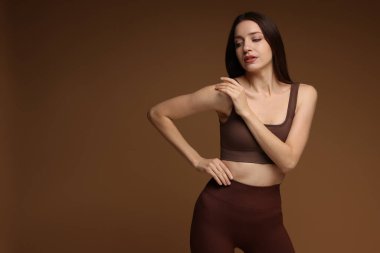 Kahverengi arka planda şık spor kıyafetleri içinde güzel bir kadın. Metin için boşluk