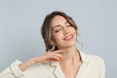 Açık gri arka planda güzel saç stili olan genç bir kadın.