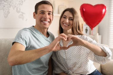 Lovely couple making heart with hands indoors. Valentine's day celebration