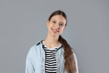 Gri arka planda gülümseyen genç kızın portresi