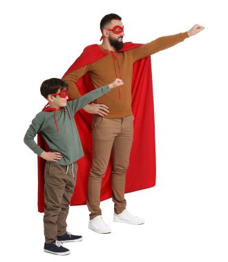 Baba ve oğlu beyaz arka planda süper kahraman kostümleri giyiyorlar.