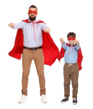 Baba ve oğlu beyaz arka planda süper kahraman kostümleri giyiyorlar.