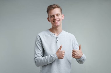 Mutlu adam gri arka planda, mesaj için boşluk gösteriyor. Jest gibi