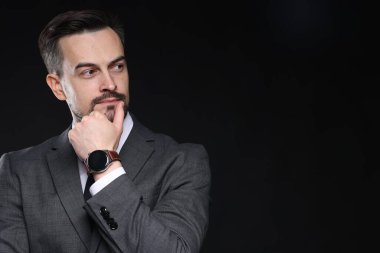 Siyah arka planda klasik takım elbiseli kendine güvenen bir adam. Metin için boşluk