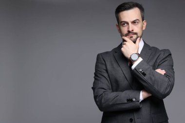Gri arka planda klasik takım elbiseli kendine güvenen bir adam. Metin için boşluk