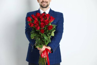 Sevgililer Günün kutlu olsun. Beyaz arka planda gül buketi olan adam, yakın plan.