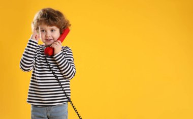 Telefon ahizesi turuncu arka planda, mesaj için yeri olan sevimli küçük bir çocuk.