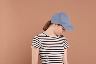 Beyzbol şapkalı, bej arka planda bir kadın. Tasarım için model