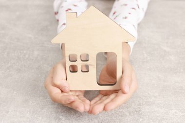 Evlat edinme. Gri masada ev figürlü küçük kız, yakın plan.