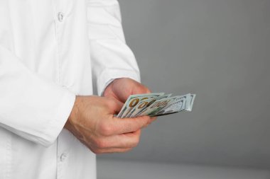 Yozlaşma konsepti. Gri arka planda dolar banknotları olan bir doktor, yakın plan. Metin için boşluk