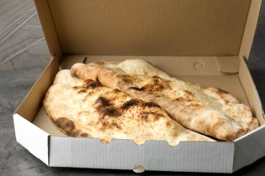 Gri desenli masadaki karton kutuda leziz calzones, yakın plan.