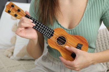 Evde yatakta ukulele oynayan bir kadın, yakın plan.