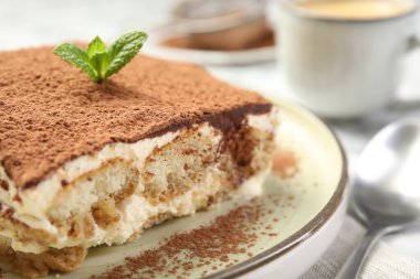 Beyaz masadaki lezzetli tiramisu parçası, yakın plan.