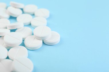 Açık mavi arka planda bir sürü antibiyotik hapı var. Yakın plan. Metin için boşluk