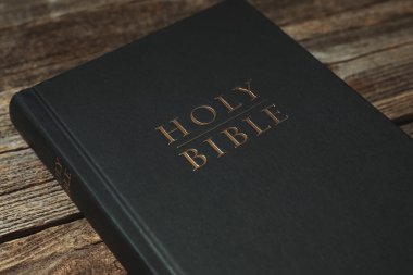 Hardcover Holy Bible on wooden table, closeup