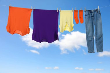 Different clothes drying on washing line against blue sky