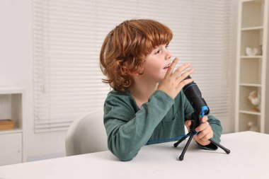 Beyaz masada mikrofonu olan küçük bir çocuk.
