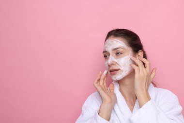 Spa günü. Yüzüne pembe arka planda maske takan güzel bir kadın. Mesaj için boşluk.