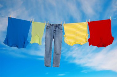 Different clothes drying on washing line against blue sky
