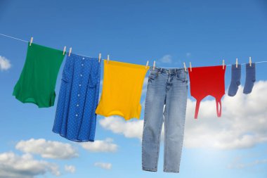 Different clothes drying on washing line against blue sky