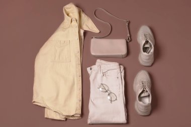 Mocha mousse arka planda çantalı şık kıyafet, düz yatış. 2025 yılının moda rengi