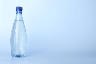 Açık mavi arka planda plastik su şişesi. Metin için boşluk