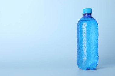Açık mavi arka planda plastik su şişesi. Metin için boşluk