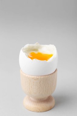 Hafif kaynamış yumurta açık gri arka planda, yakın plan.