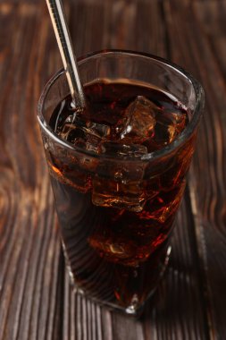 Buz küplü soğuk kola ve ahşap masada saman içmek, yakın plan.