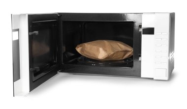 Mikrodalga fırını aç ve beyaz üzerine izole edilmiş patlamış mısır torbası koy.