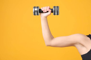 Turuncu arka planda halterli bir kadın egzersiz yapıyor, yakın plan. Metin için boşluk