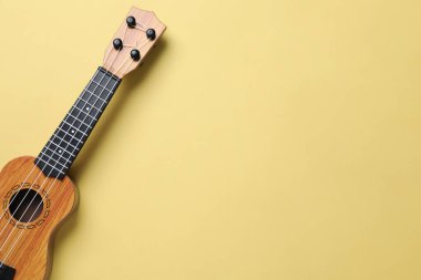 Soluk sarı arka planda bir ukulele, üst manzara. Metin için boşluk