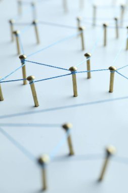 Ağ bağlantısı. Çiviler beyaz masadaki iplikle birbirine bağlanıyor. Yakın plan.