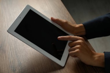 İş kadını, kapalı bir masada tablet kullanıyor, yakın plan. Modern teknoloji